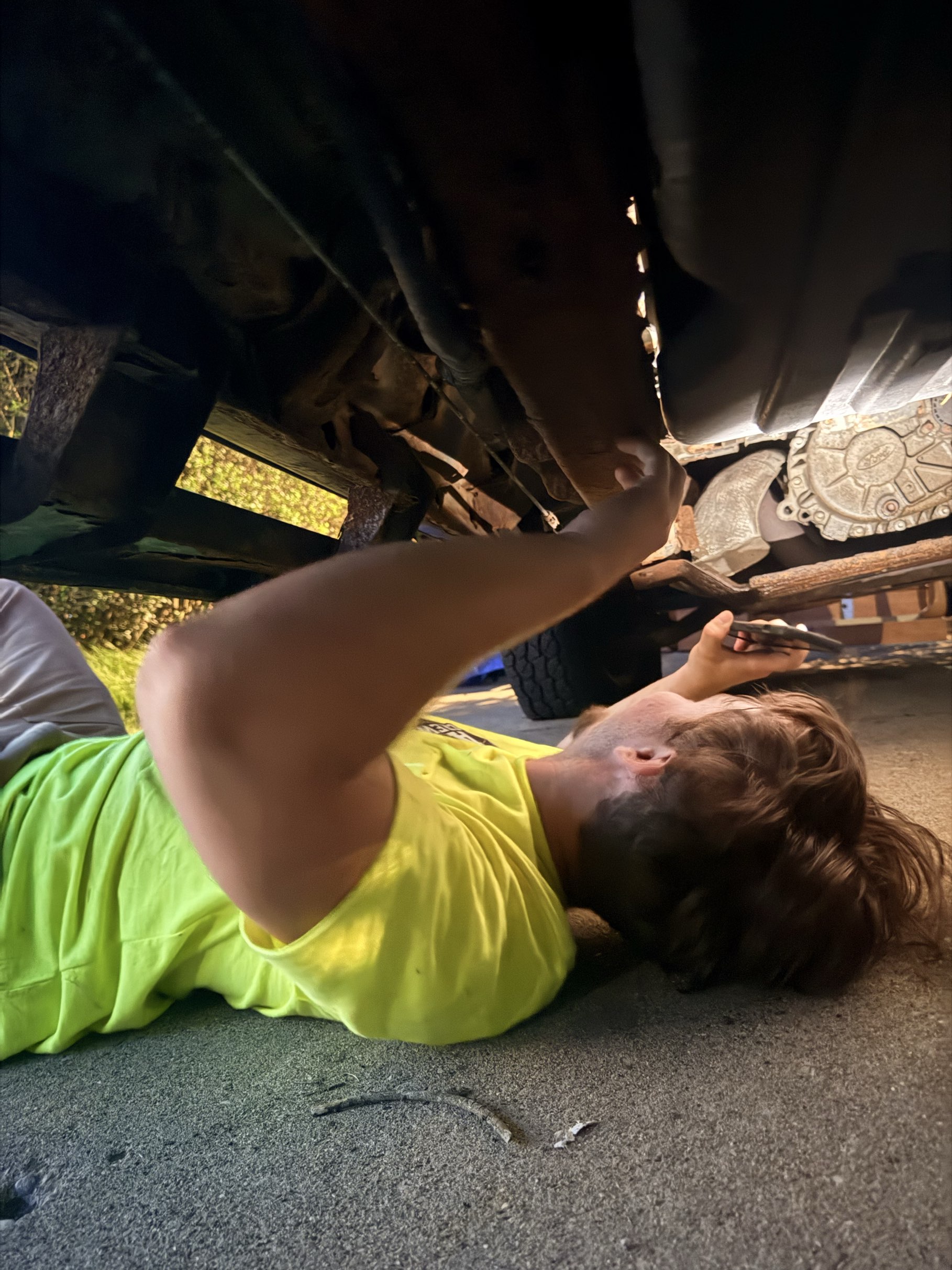 A+ Crew member doing hands-on repair work under a vehicle