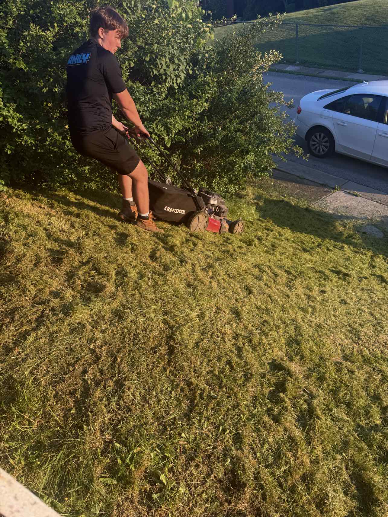 A+ Crew member mowing a steep grassy hillside