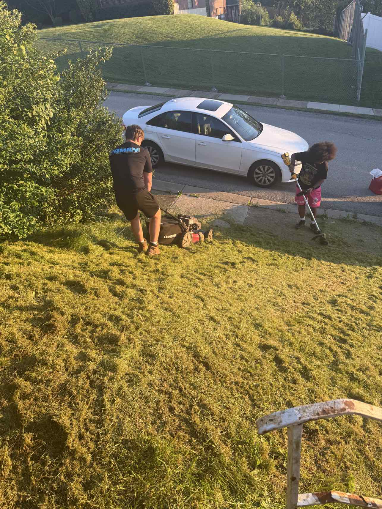 Two A+ Crew members mowing and trimming a yard together